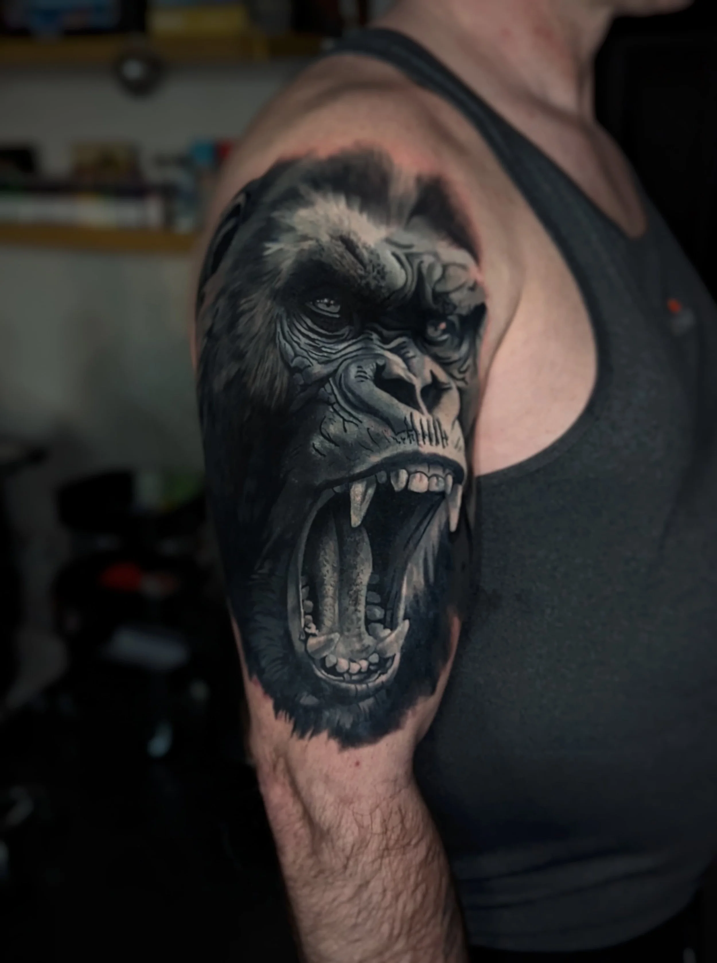 Tattoo of a roaring gorilla on a man's upper arm and shoulder