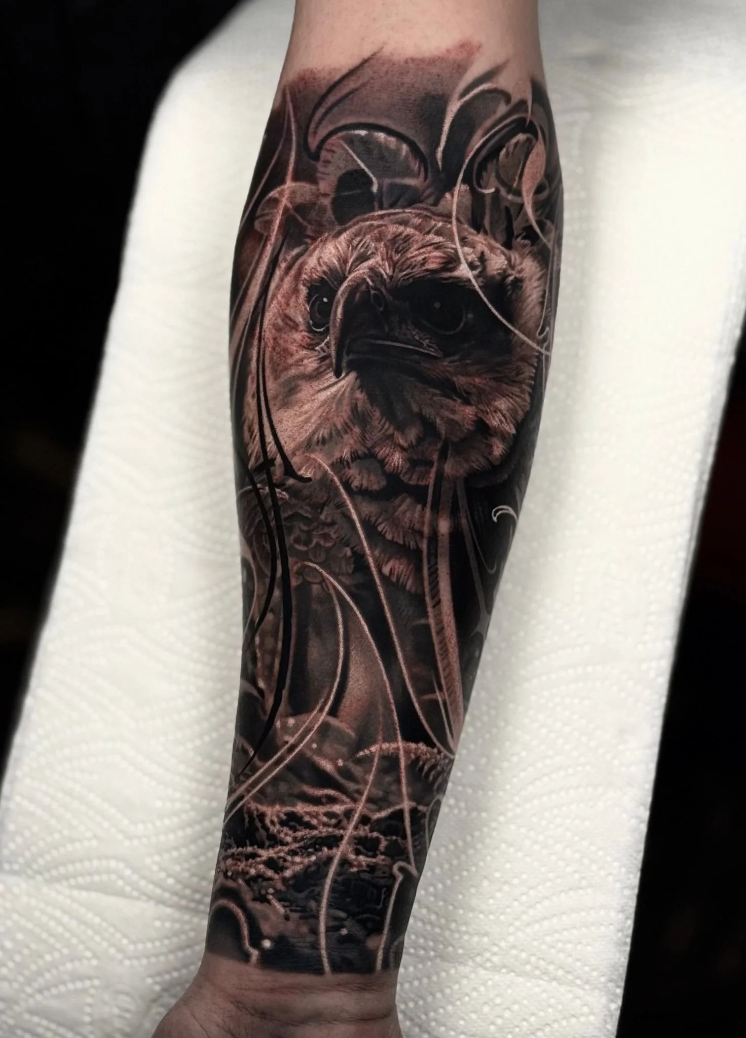 Black and gray realistic tattoo of an owl on a person's arm.