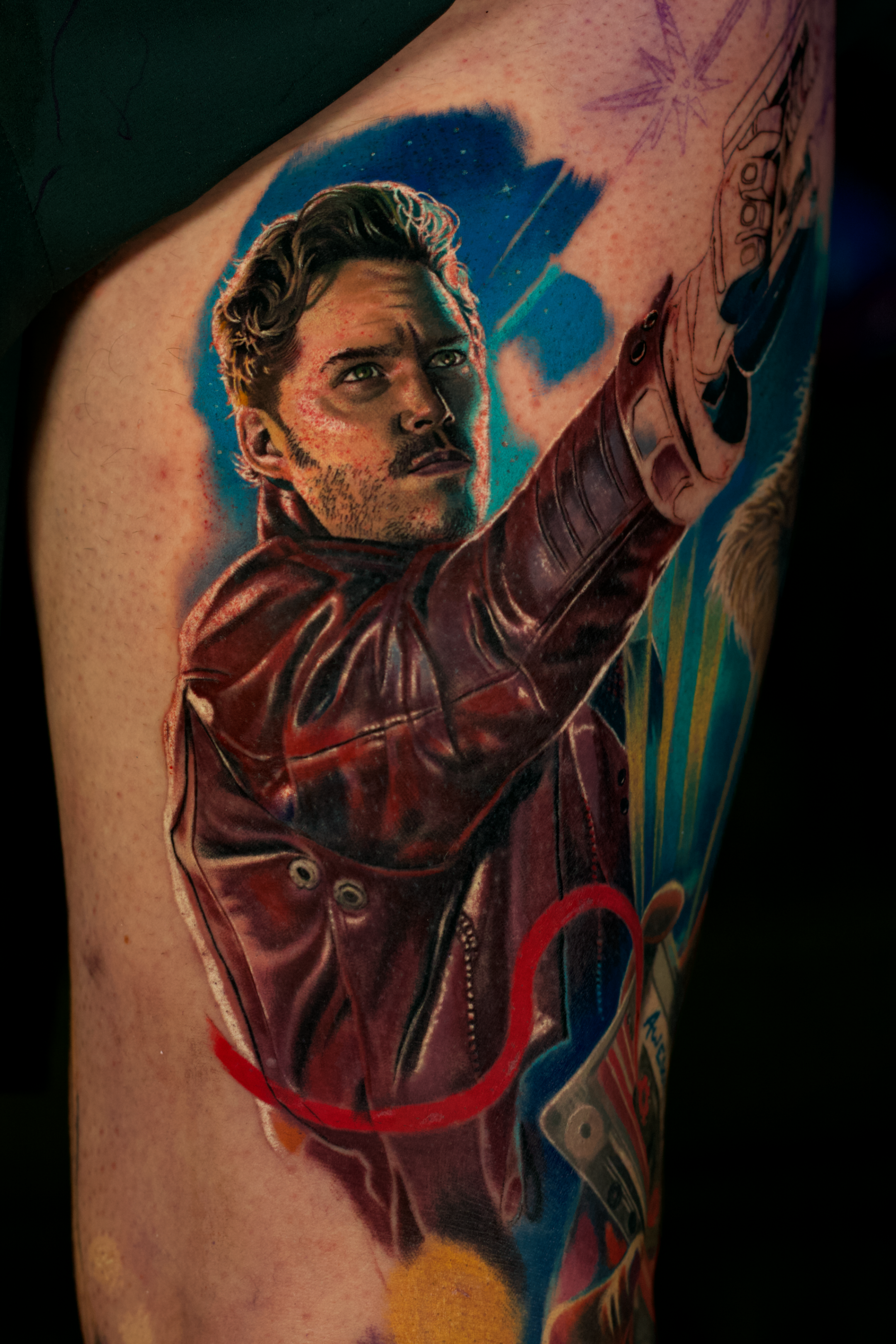 Colorful tattoo of Star-Lord from Guardians of the Galaxy on a person's upper arm.