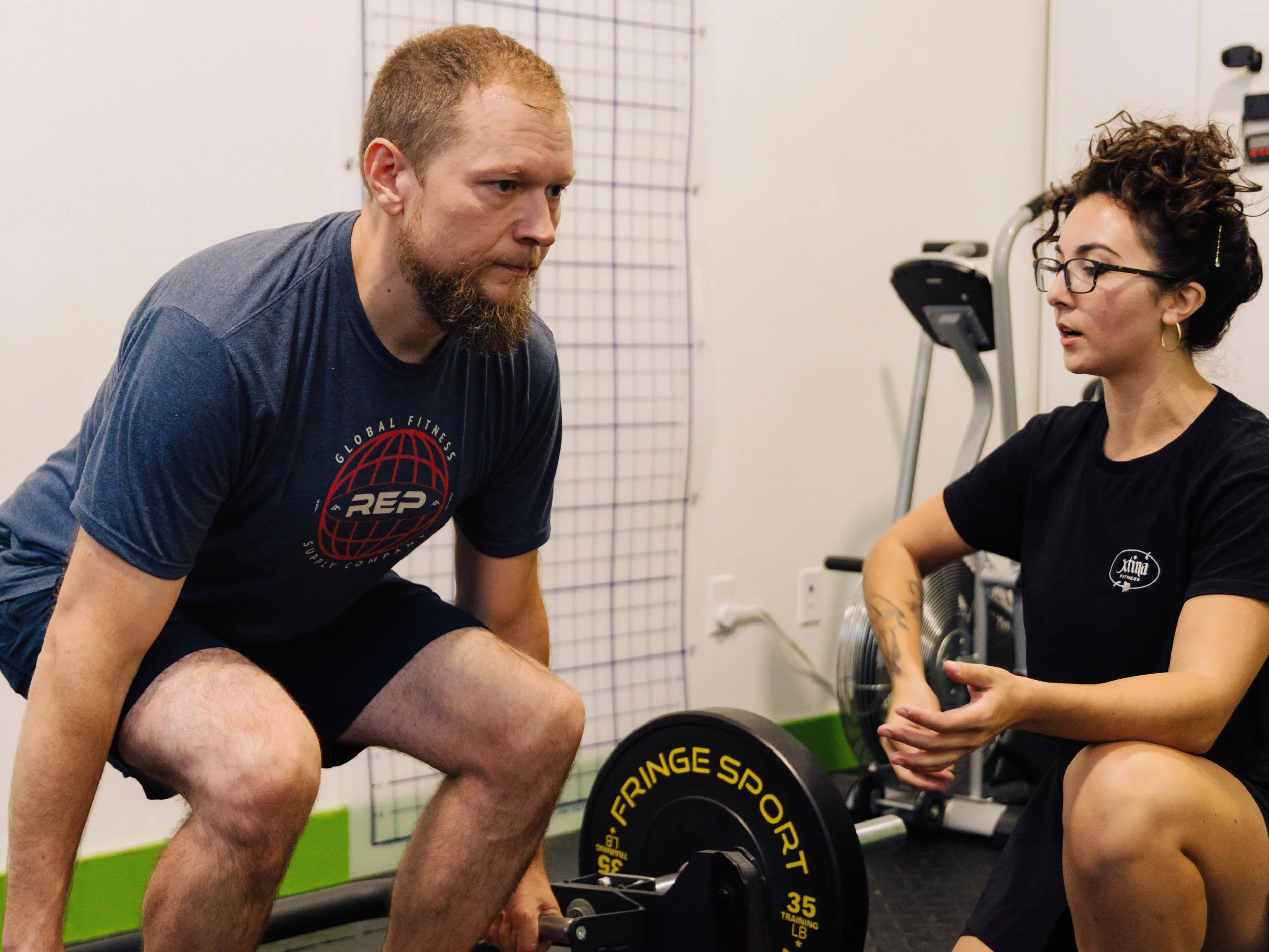 Man smiling working out on bench with trainer