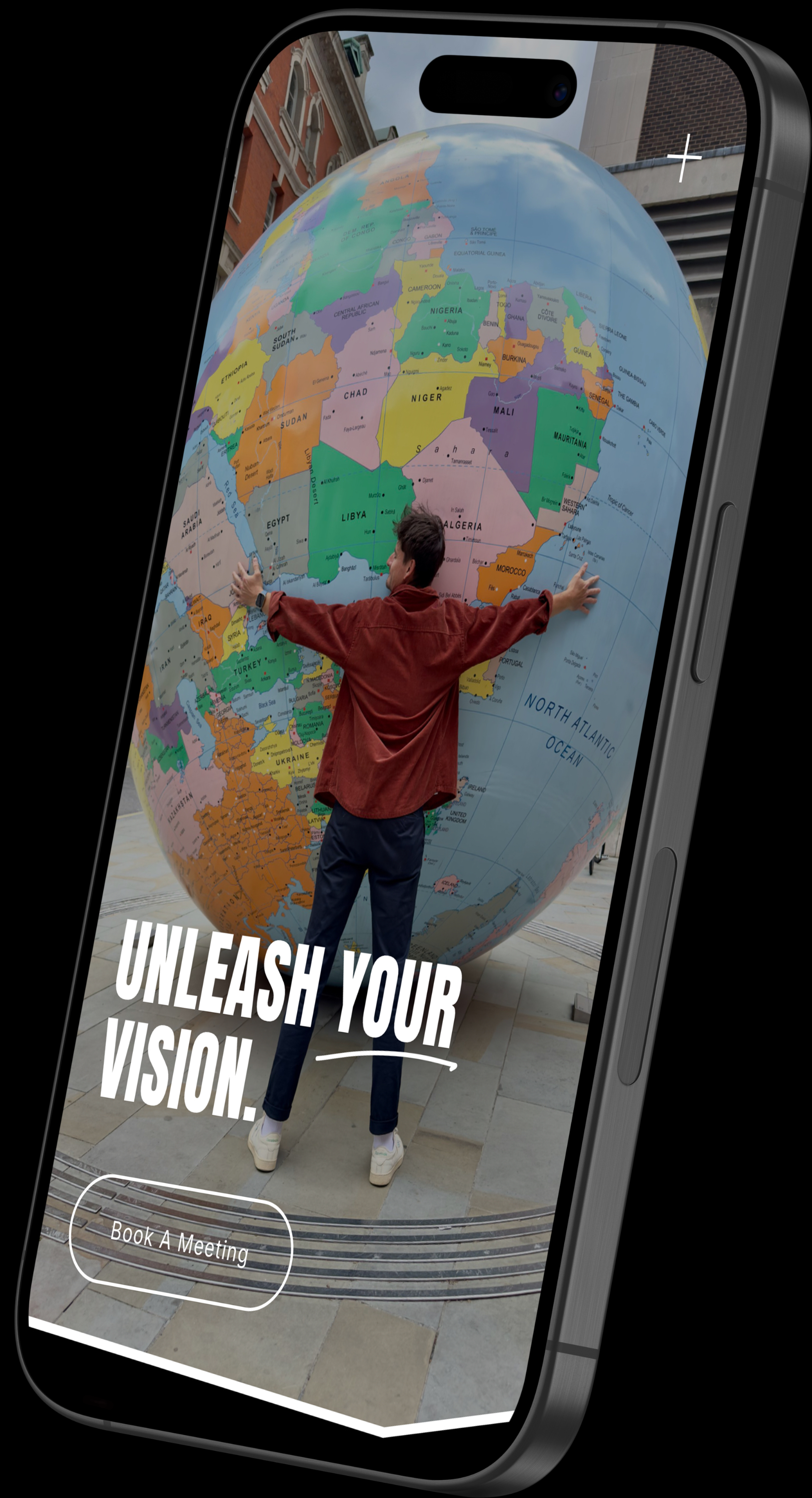 Tommy Pratt embracing a large globe displayed on a smartphone screen with the message “Unleash Your Vision”, representing The Pratt Studios’ architecture, interior design and aerial imaging services.