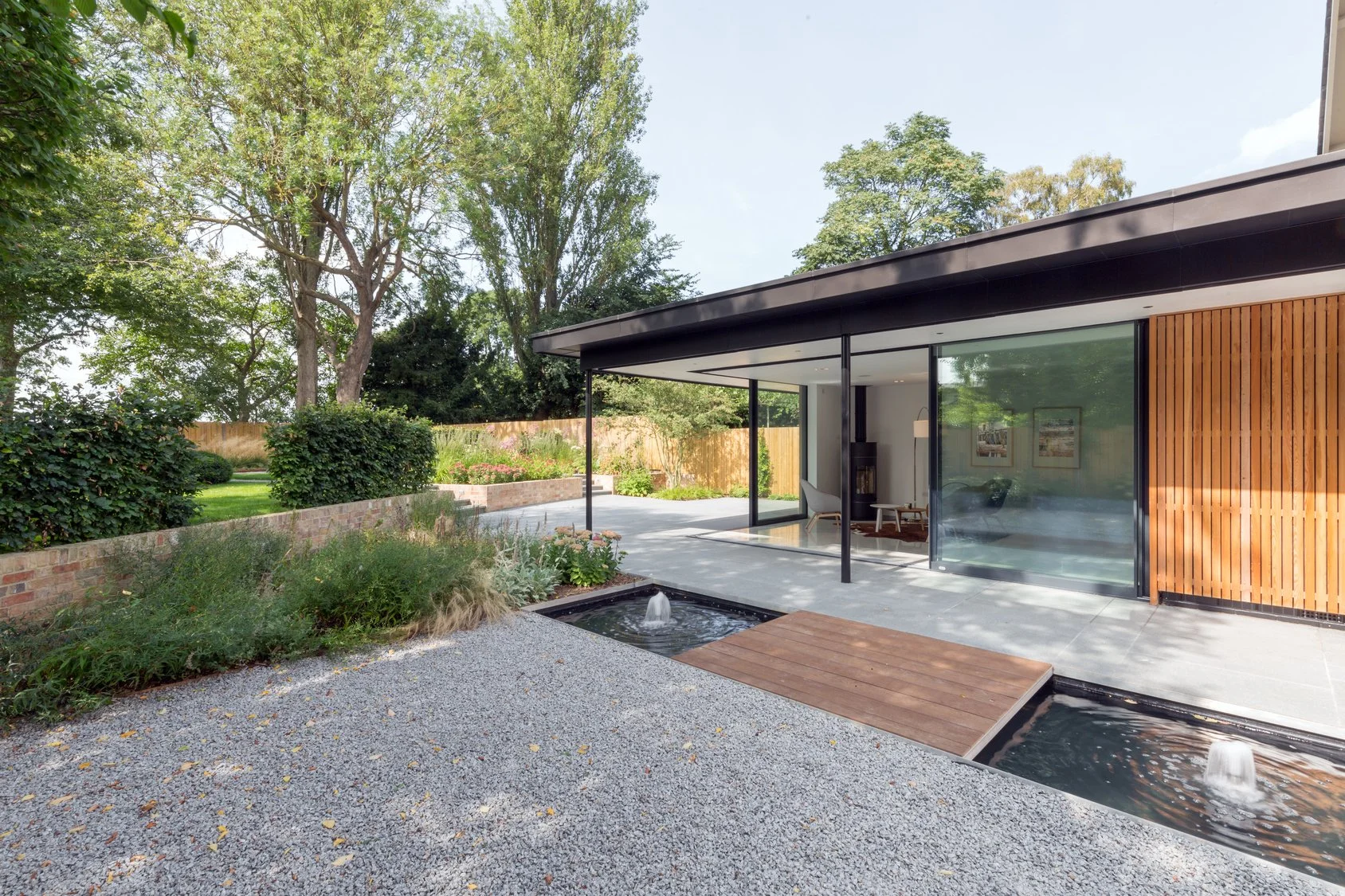 Contemporary single-storey home extension with large glazed openings, landscaped garden and modern residential architectural design.