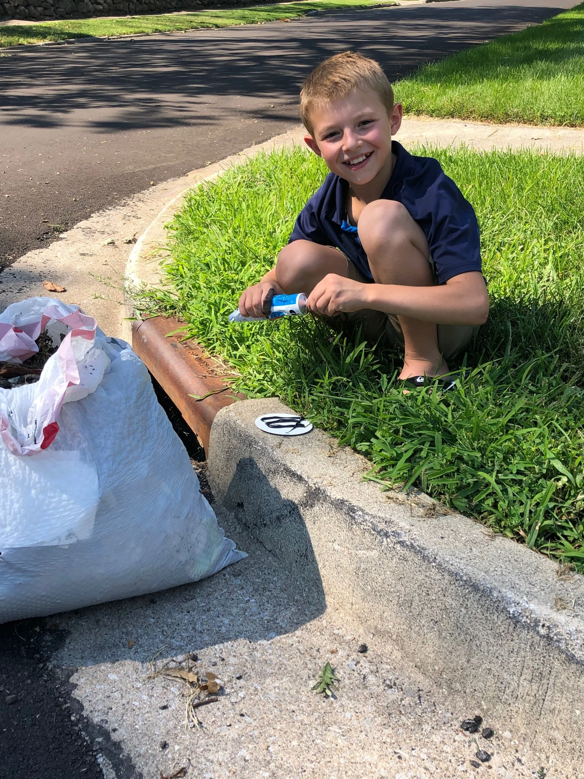 A young boy cleaning the storm drains outside his home.
