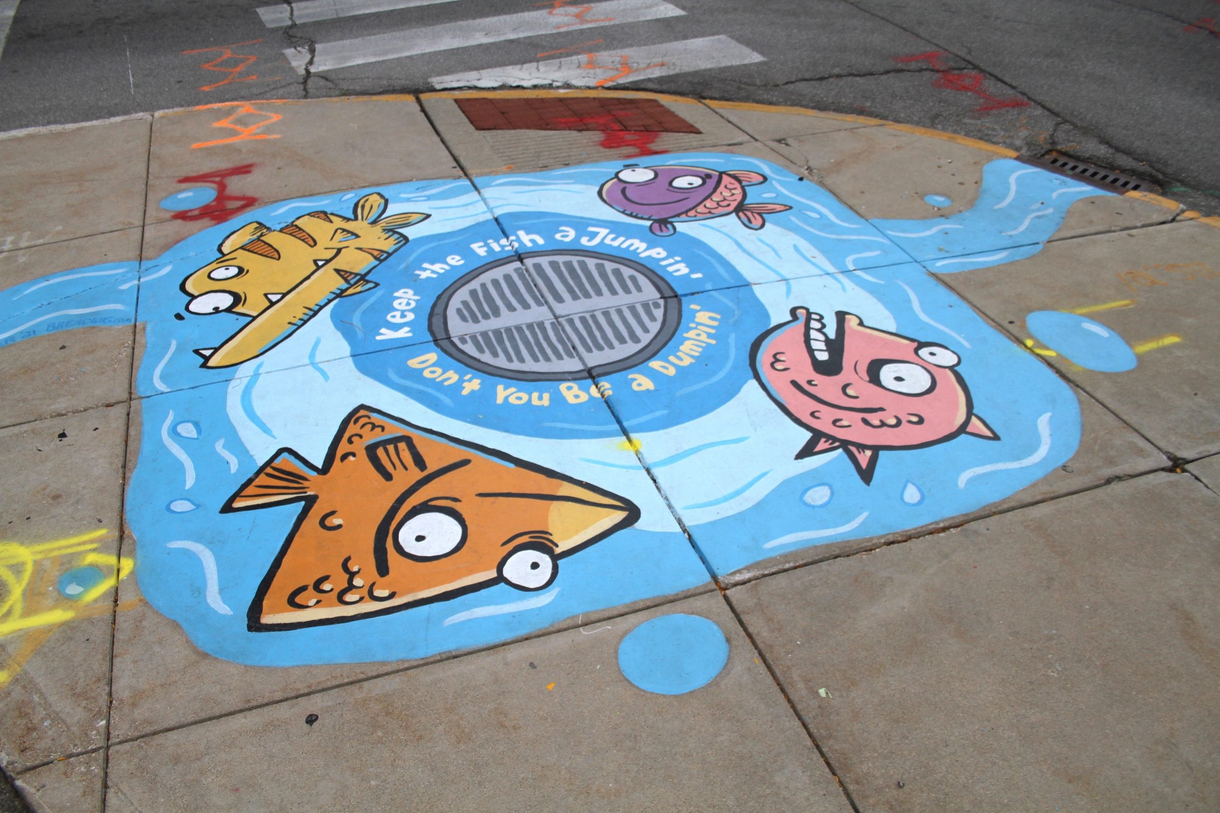 Storm drain art mural of 4 carytoon fish and the words "Keep the fish a jumpin', don;t you be a dumpin'".