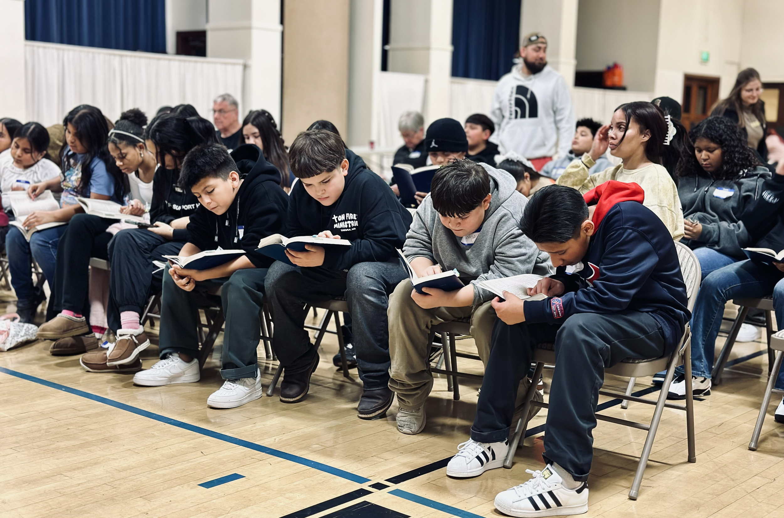 Group of children seated and reading books during an indoor event.