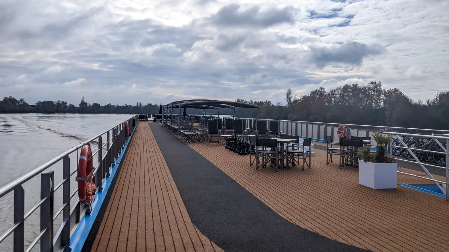The sun deck of a river cruise ship on a quiet day, lined with seating