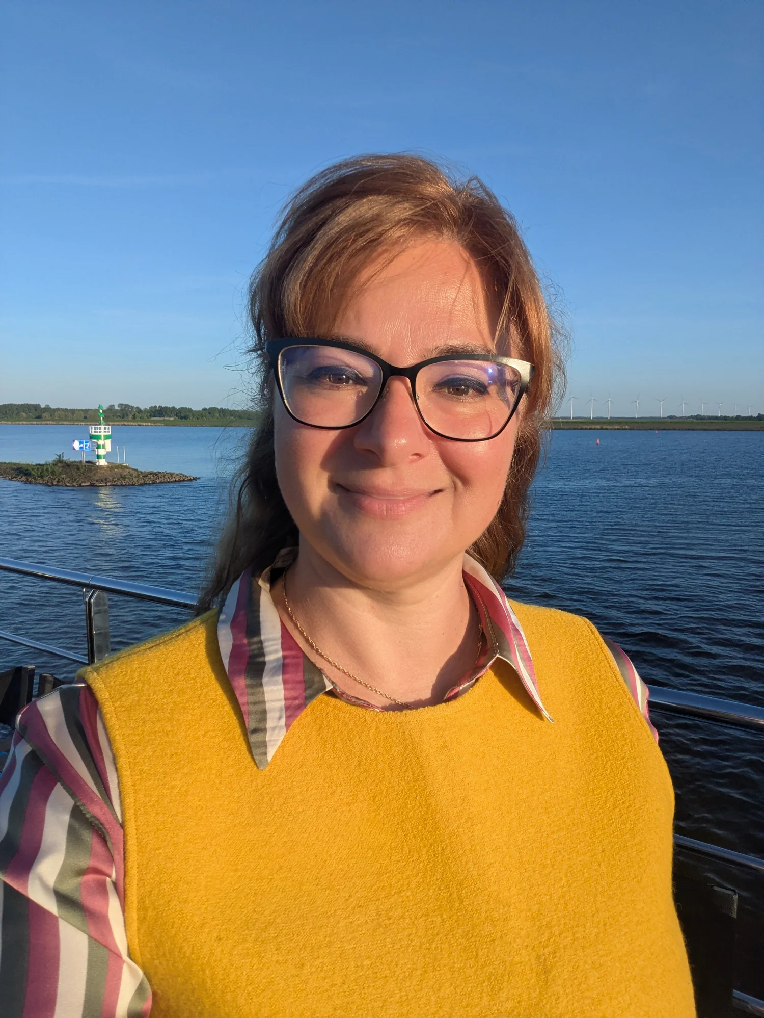 Maddy Căldărușe on the deck of a river cruise ship in evening sun, with the river behind her