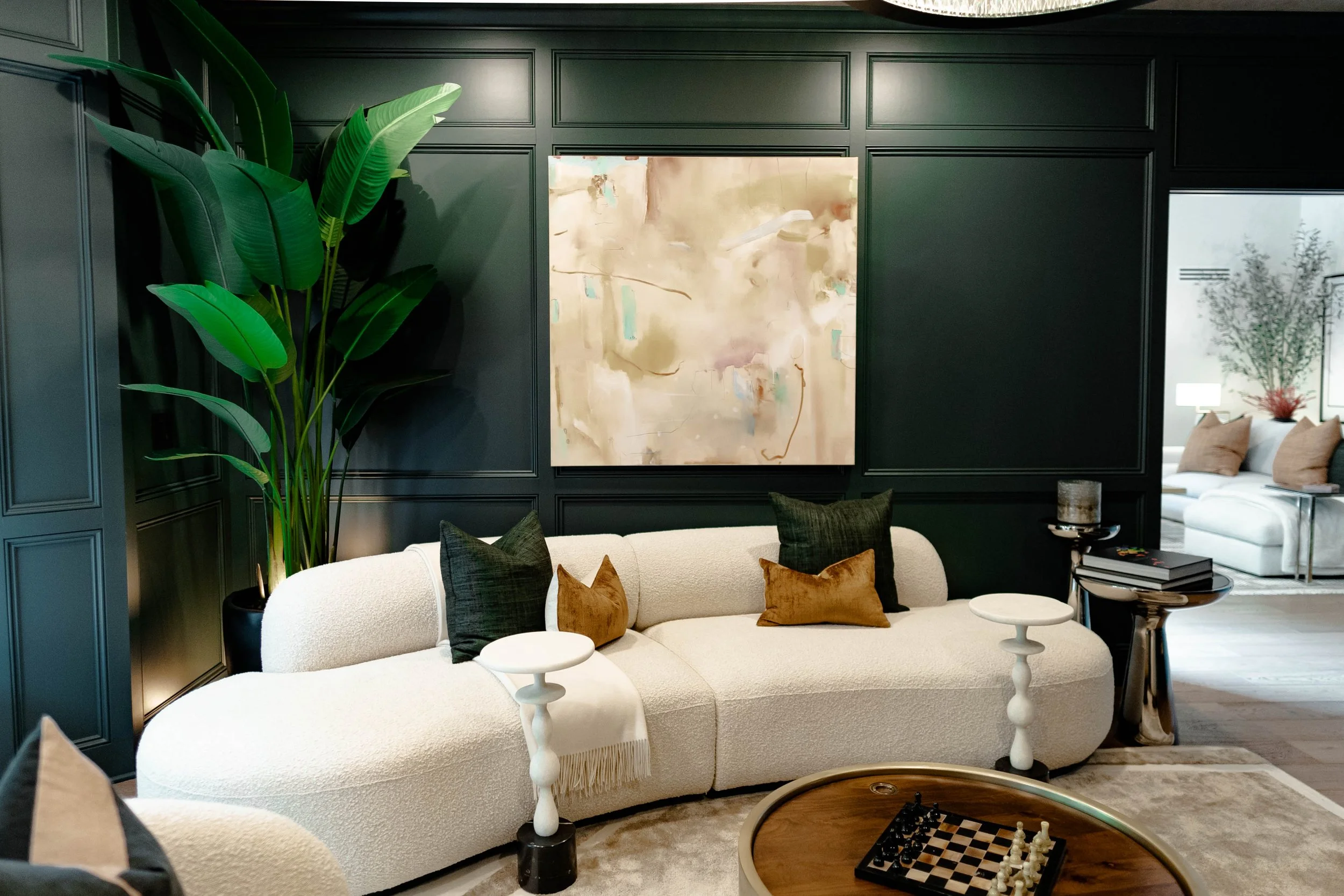 Curved white sofa with abstract art and dark green wall paneling Beaumont Green