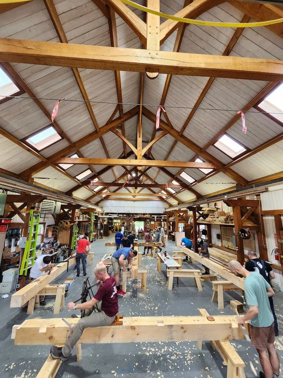 Bustling workshop of students learning to cut a timber frame.