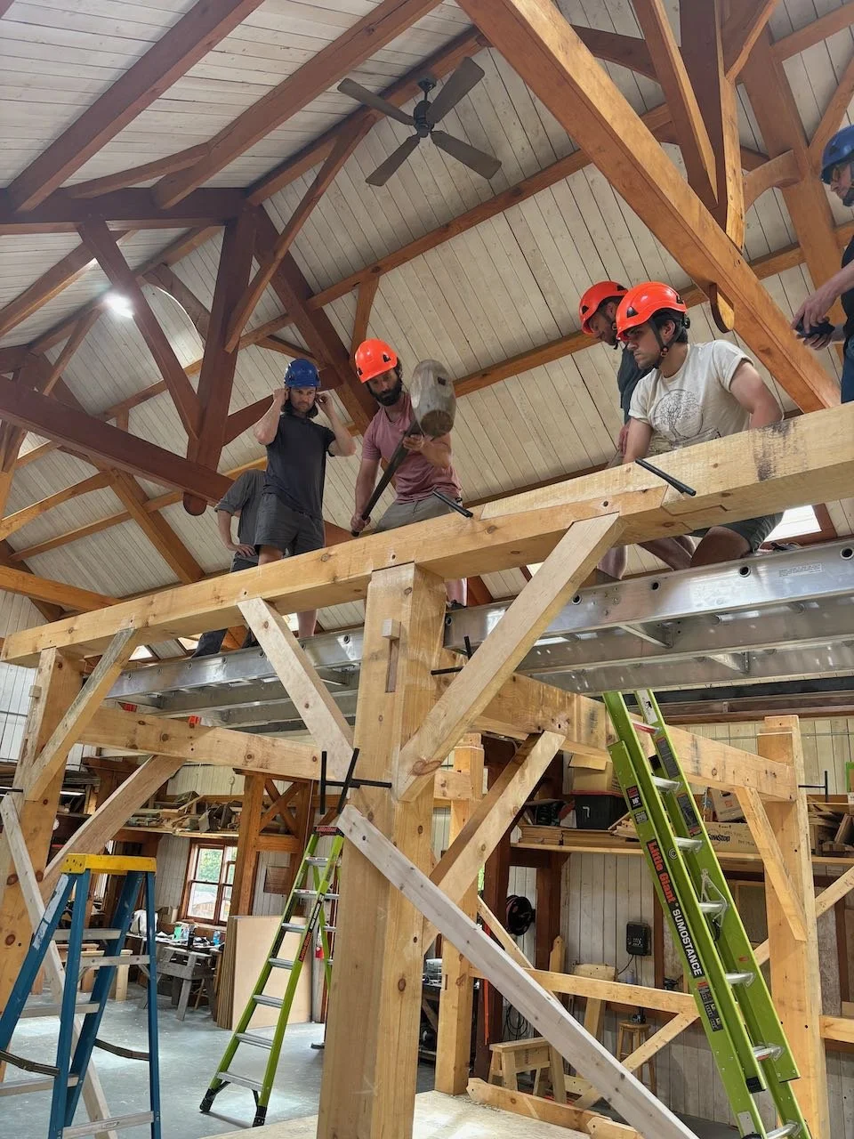 Students on staging learning to raise a timber frame