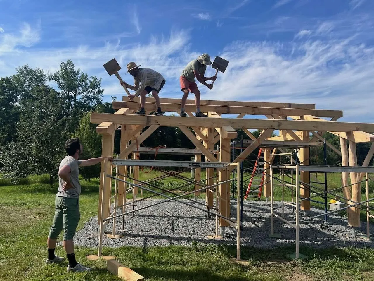 Timber frame raising with silhouette of two carpenters on roof with giant hammers