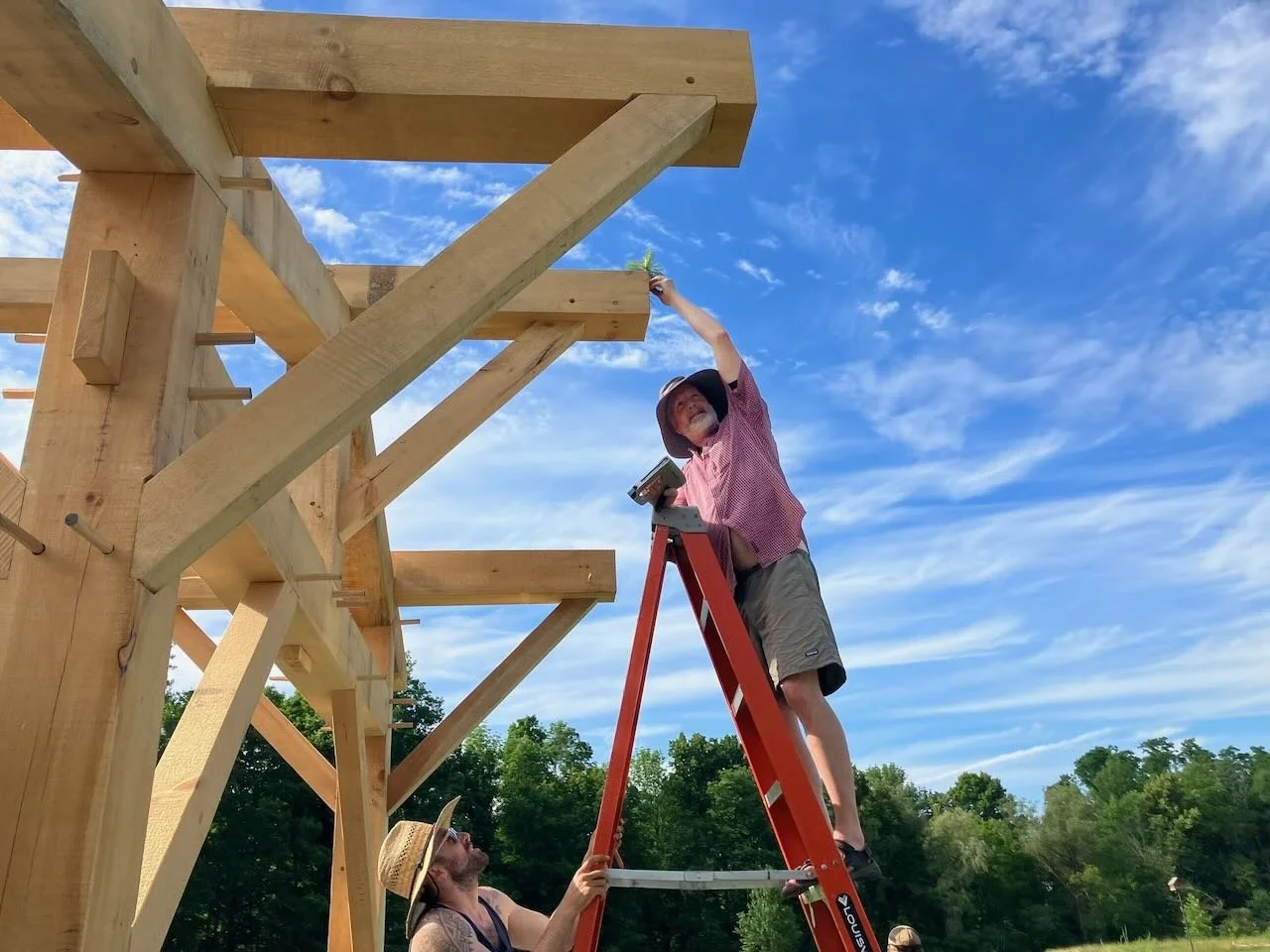 Carpenter on ladder at timber frame raising