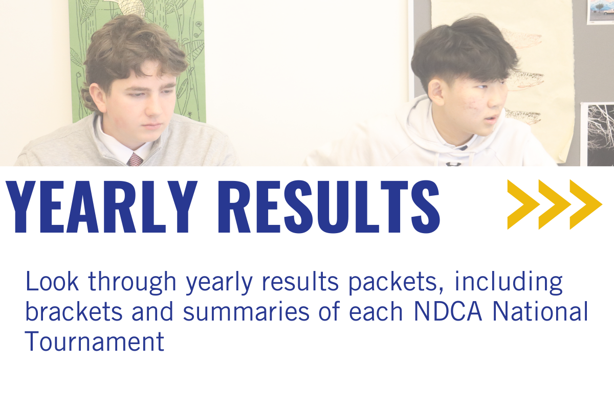 Two young boys sitting at a table in a classroom or office, with posters and papers on the wall behind them, during a presentation or meeting about yearly results.
