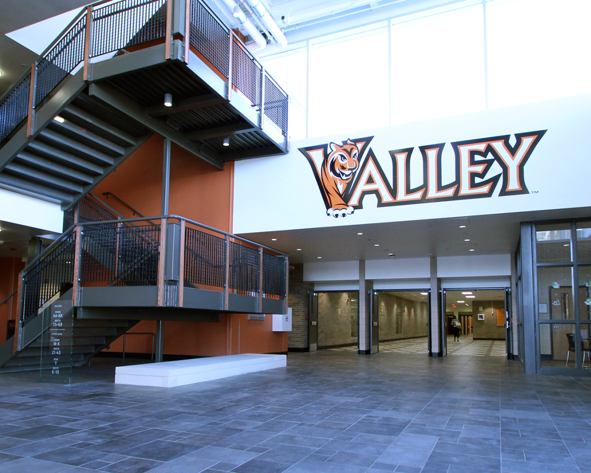 Interior of a modern building with a large logo that reads 'Valley' and a tiger mascot, featuring a staircase and open lobby area.