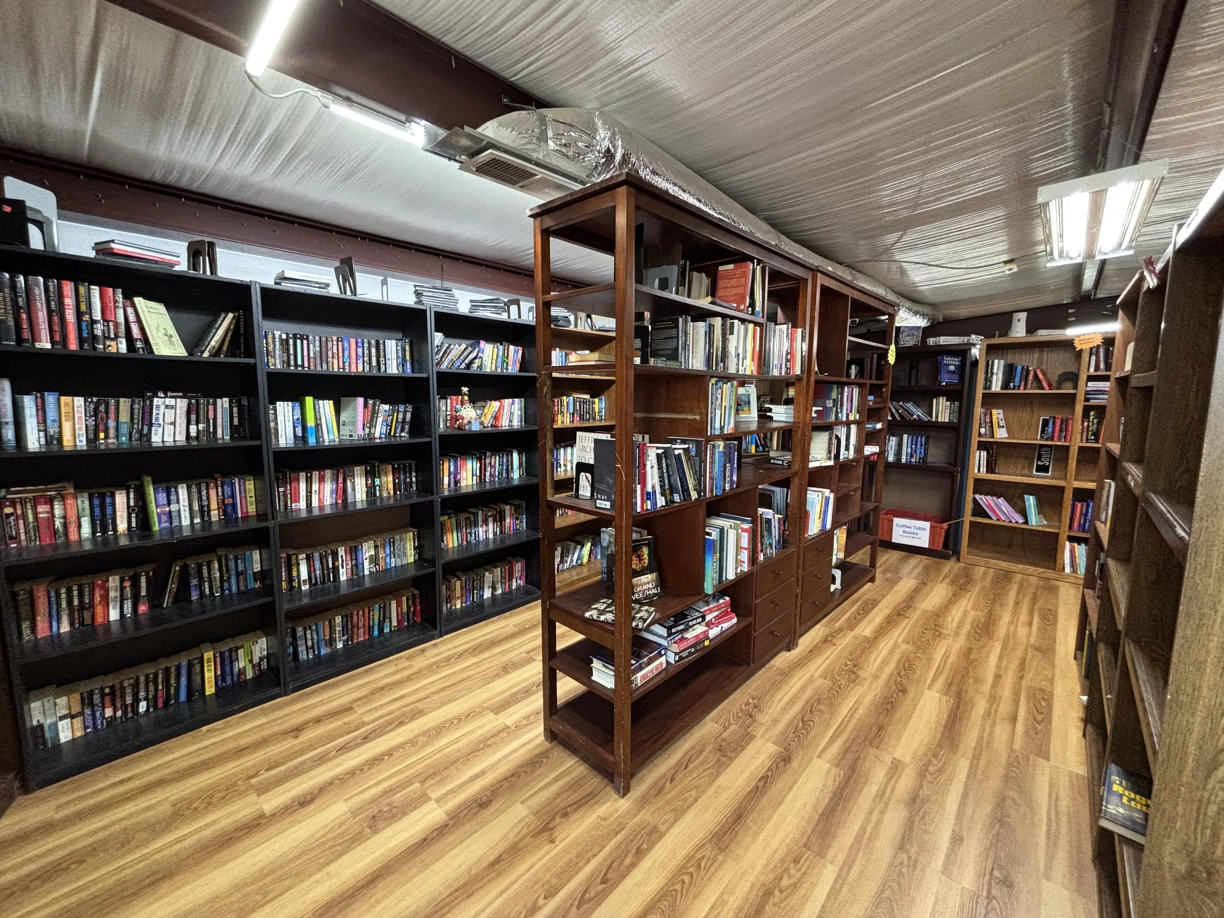 Bookshelves filled with books in a bookstore or library with wooden floors and a wooden ceiling.