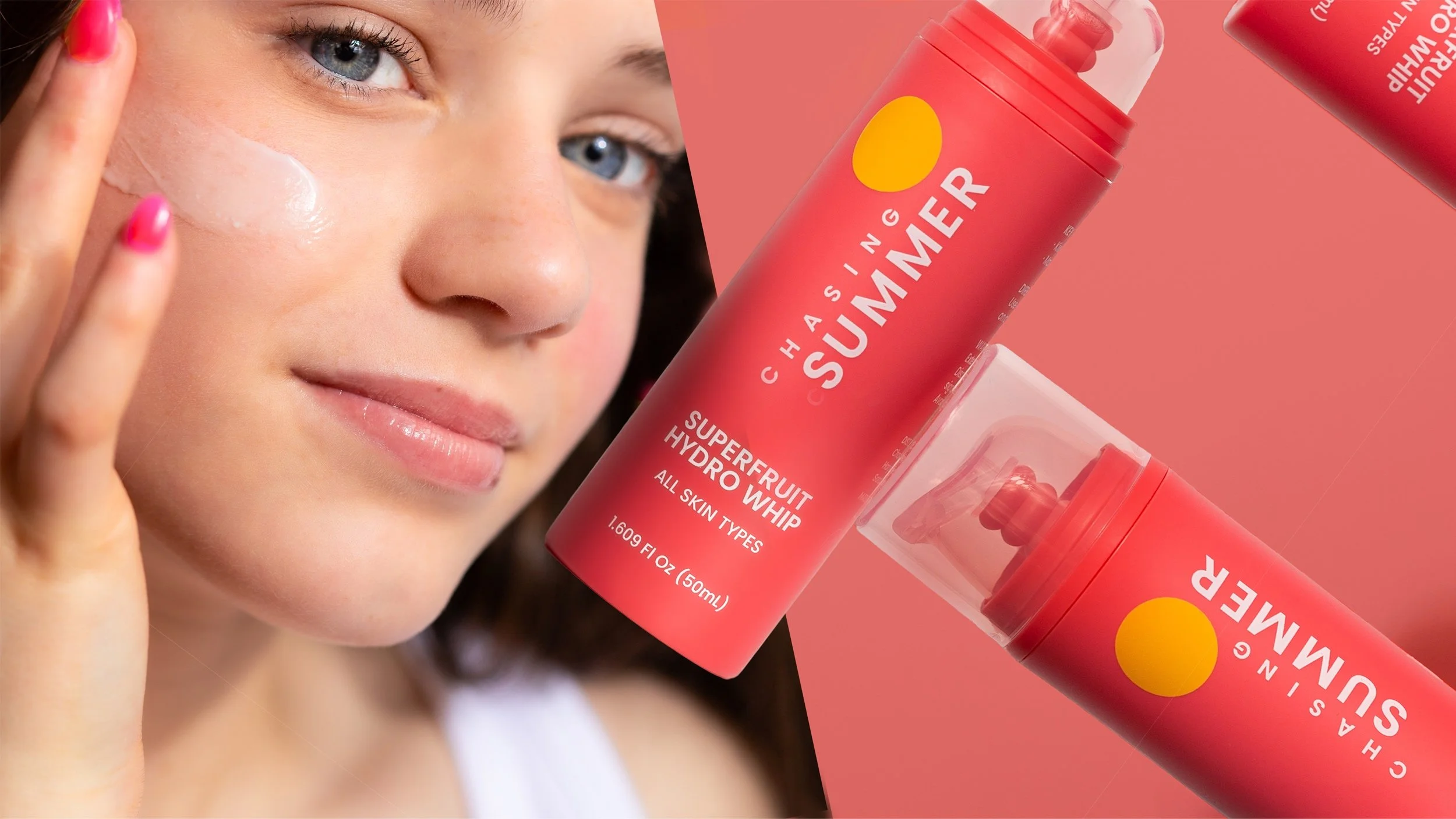 A woman with fair skin, light blue eyes, and pink nail polish is applying face moisturizer to her face. Next to her is a large pink spray bottle labeled 'Chasing Summer Superfruit Hydro Whip' indicating it is suitable for all skin types.
