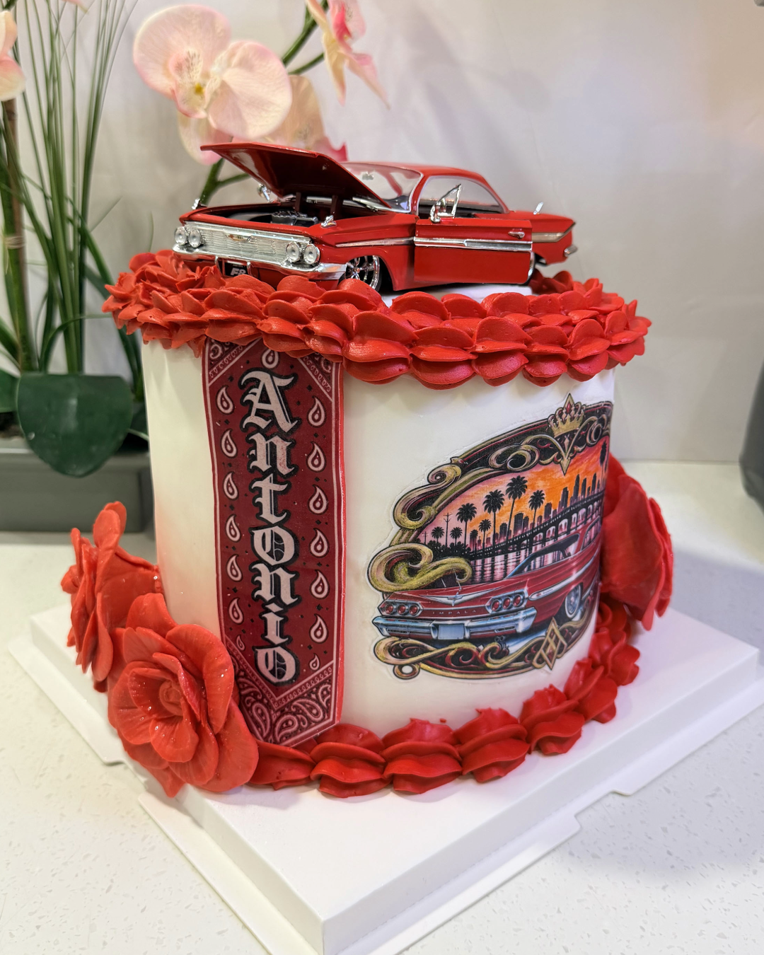 Custom Chicano Lowrider cake featuring a classic lowrider car, red roses and tattoo-inspired details. Custom birthday cakes in Pueblo, Colorado.