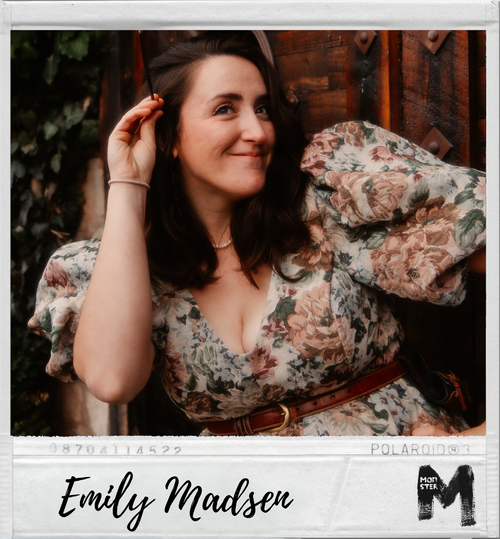 A woman with dark hair wearing a floral dress with puffy sleeves, smiling and posing outdoors.