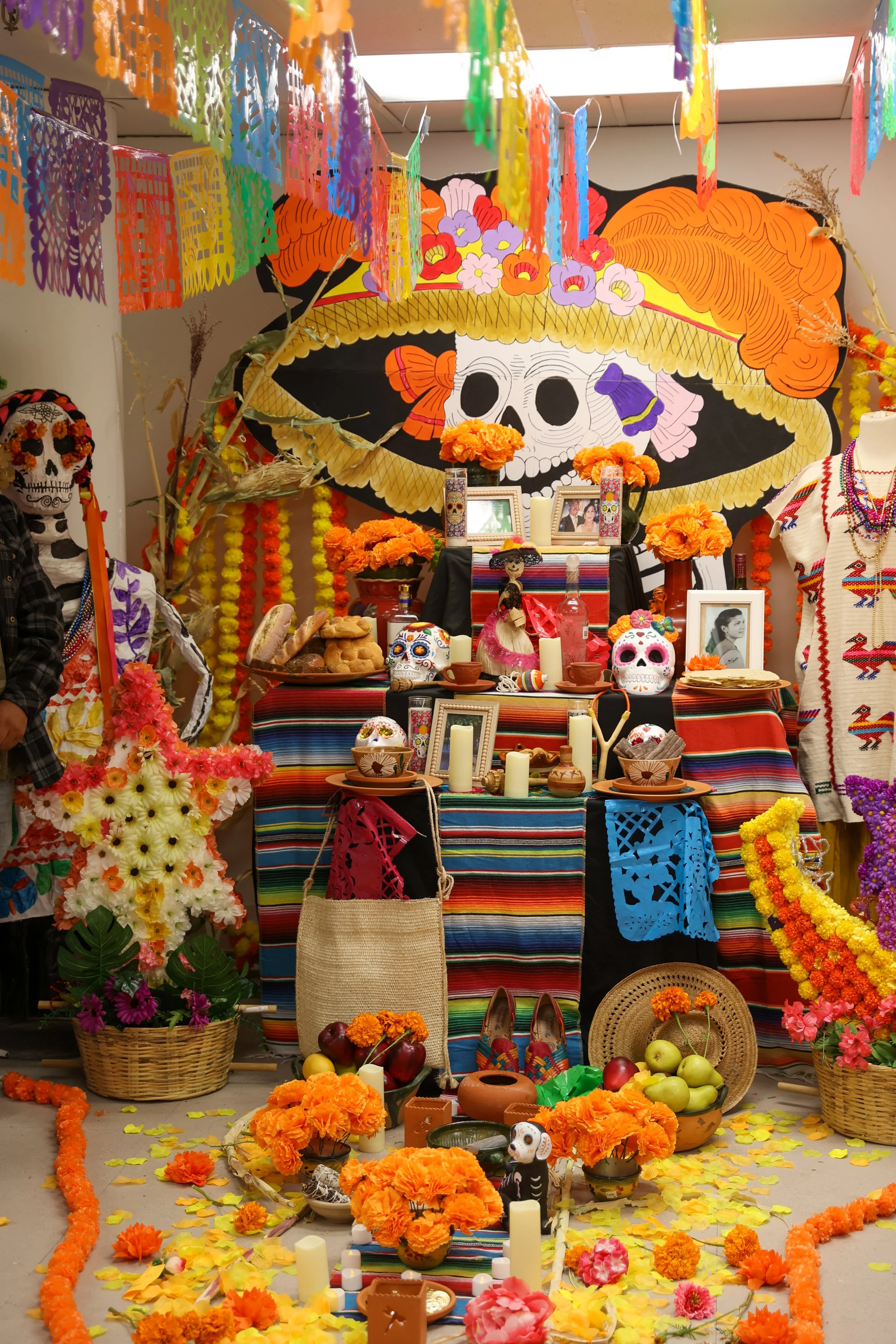 Altar decorado com flores coloridas, velas, caveiras e itens tradicionais mexicanos para a celebração do Día de los Muertos.