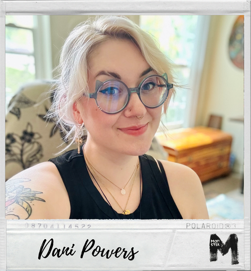 Close-up of a young woman with blonde hair, glasses, and a nose ring smiling indoors."}