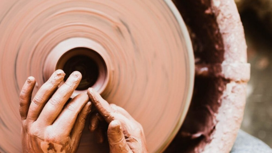Mãos moldando argila numa roda de oleiro.