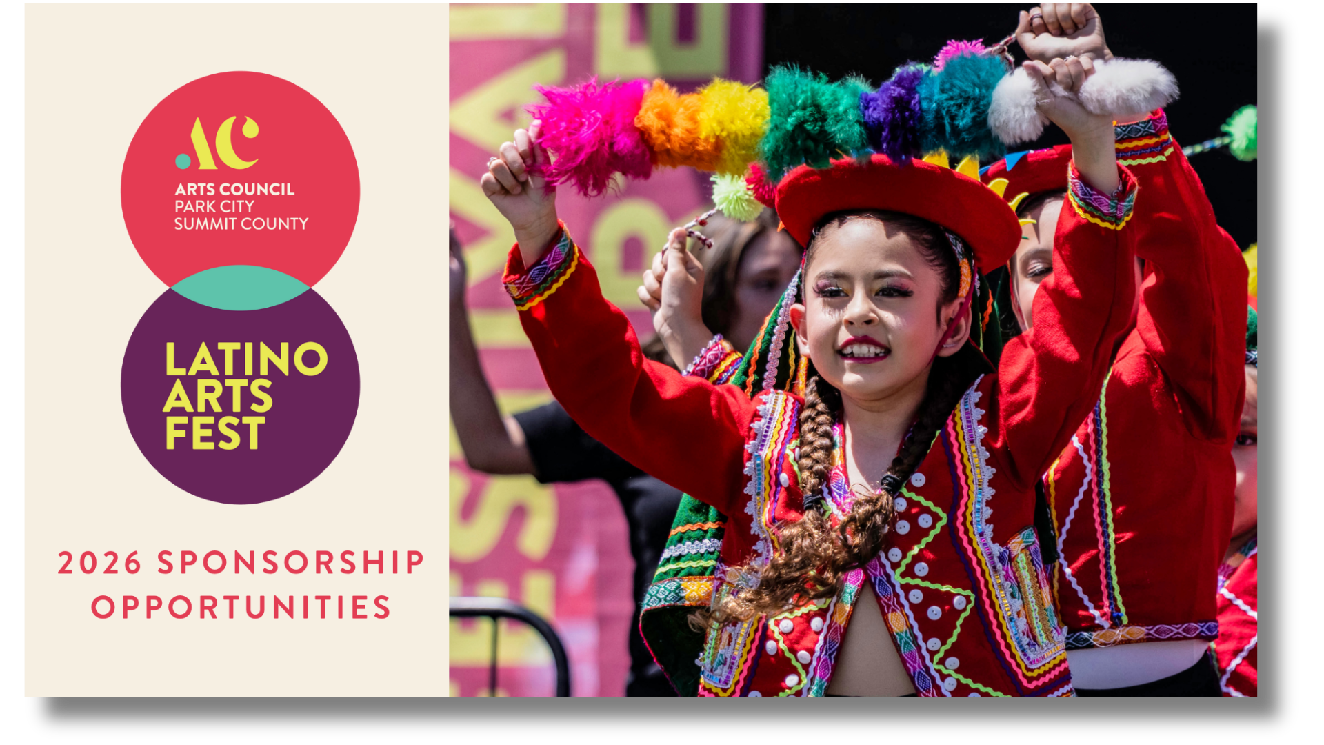 A young girl in traditional colorful attire playing a percussion instrument at a cultural festival, with other performers in the background.