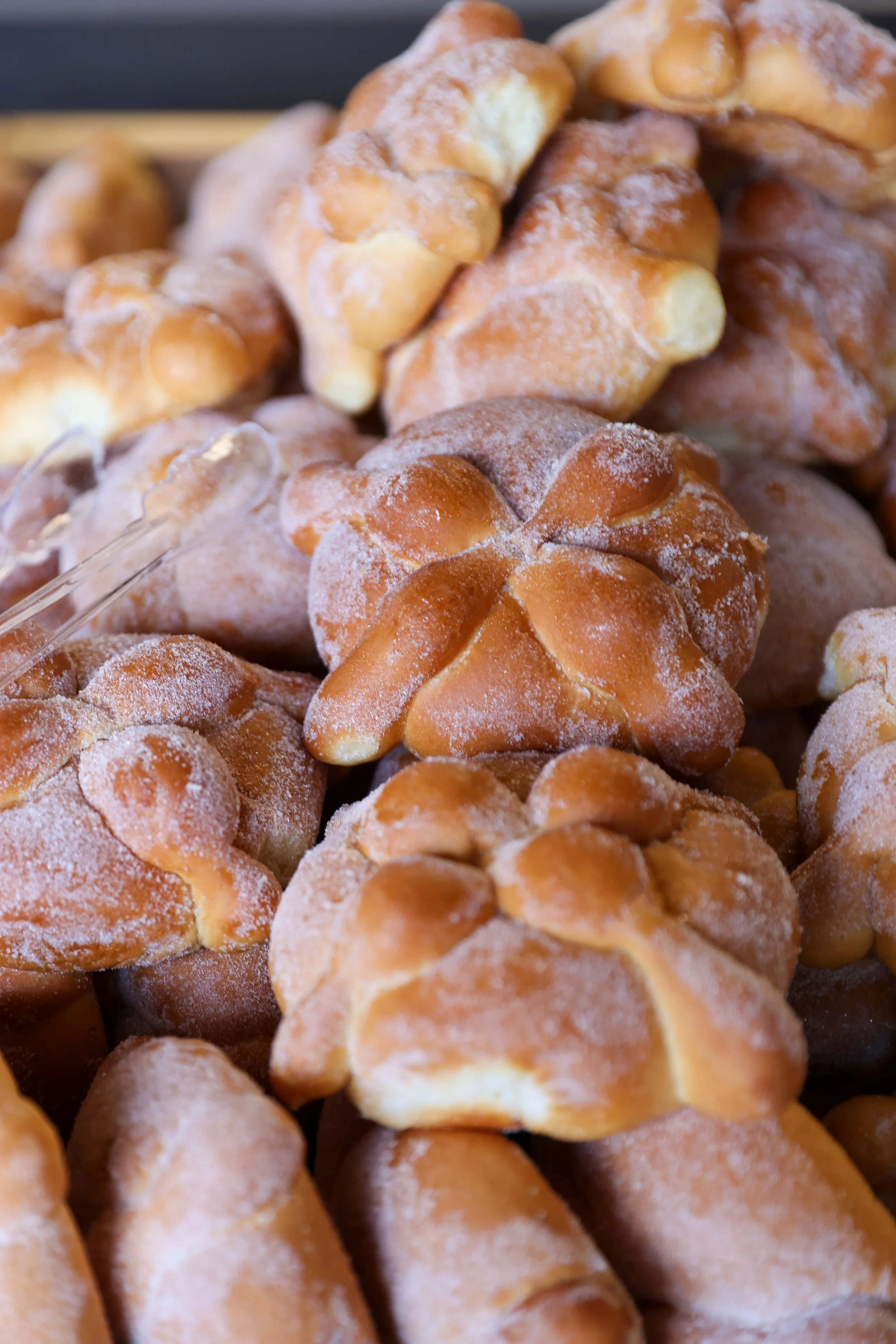 Close-up de uma pilha de pão tradicional assado chamado «Pan de Muerto», polvilhado com farinha.