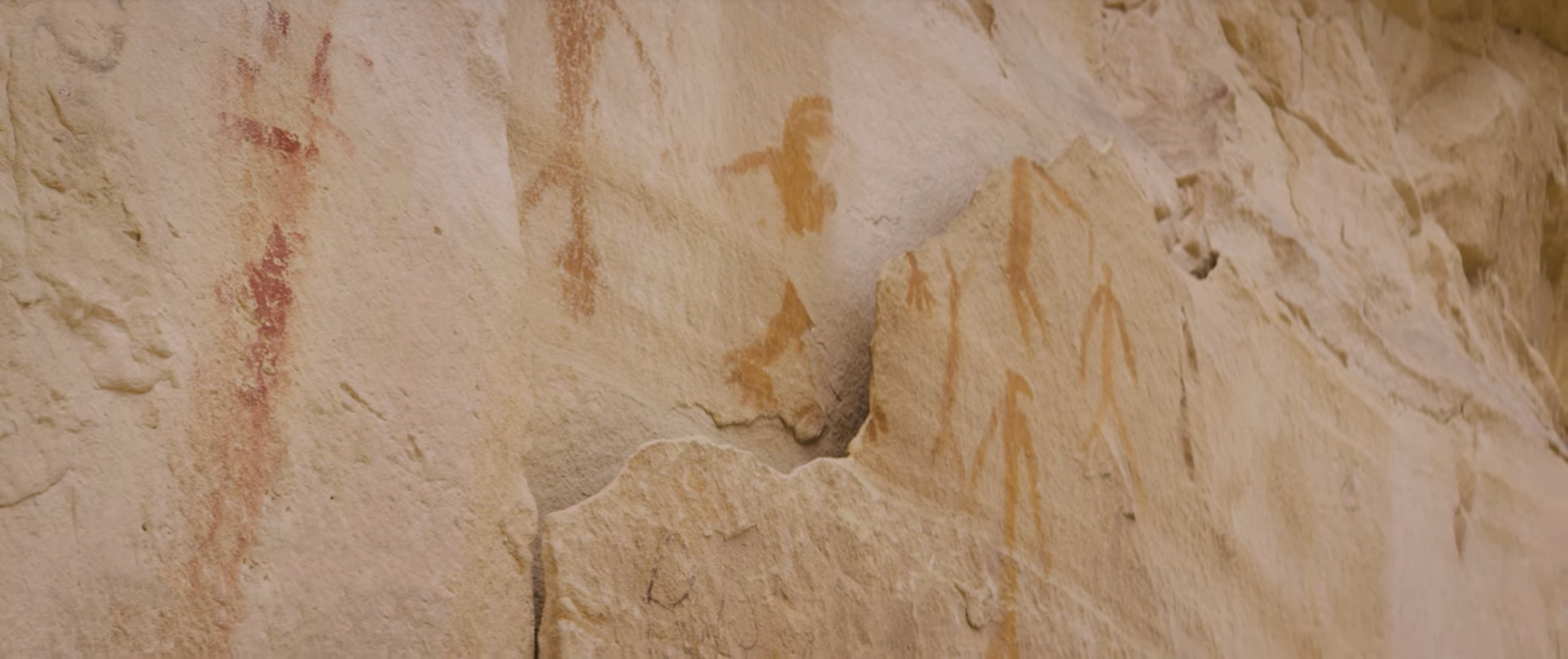 Close-up of a textured beige and cream stone wall with orange streaks and markings.