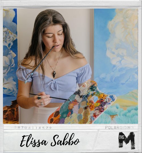 Young woman with long brown hair painting on a colorful canvas, wearing a light blue off-the-shoulder top, standing in front of blue and yellow sky landscape paintings.