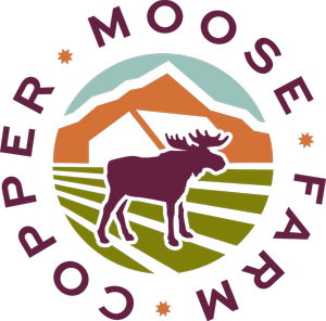 A logo featuring a purple moose standing on green grass with mountains in the background and the words 'Copper Moose Farm' encircling the scene.