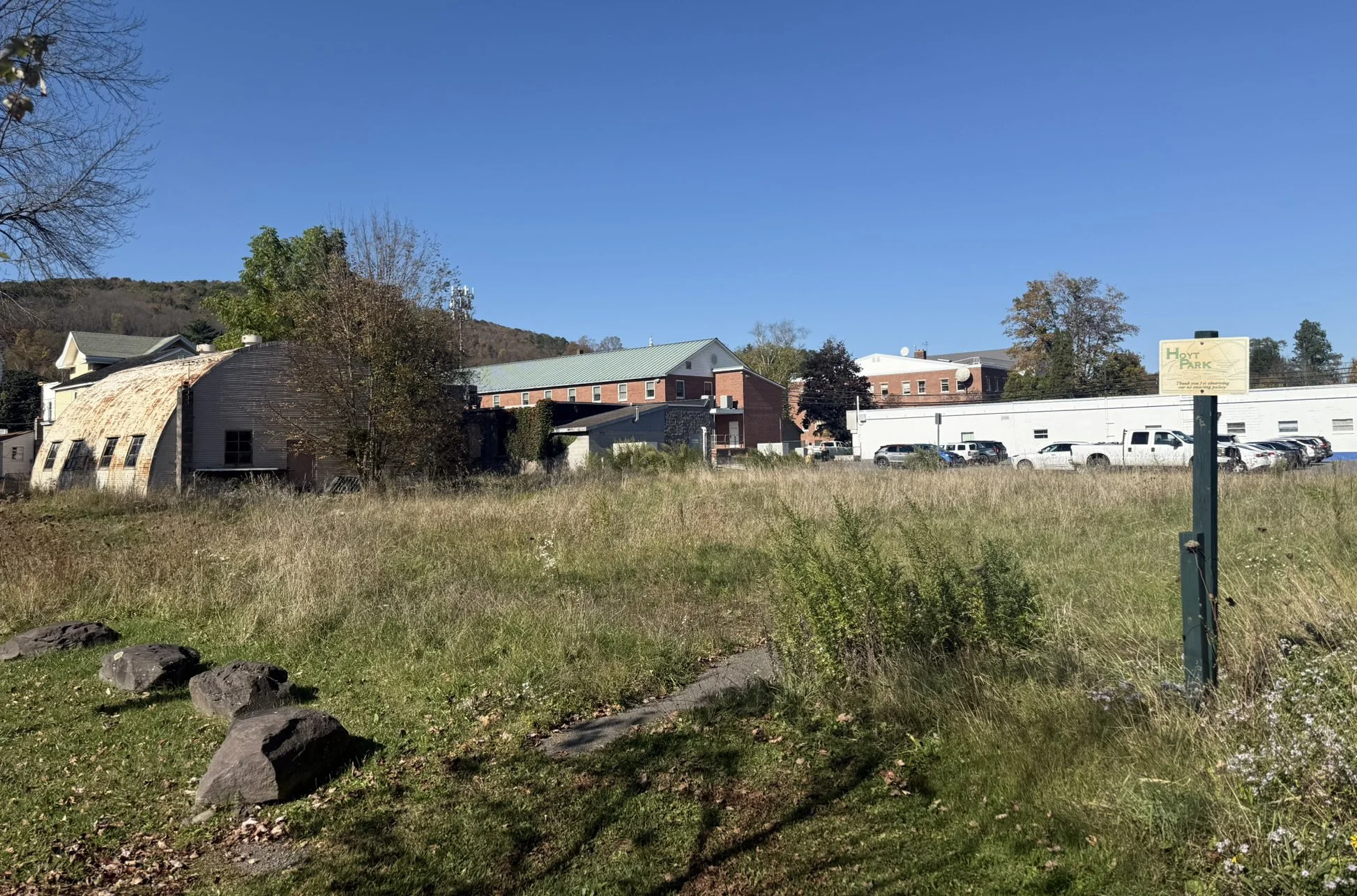 Existing vacant lot adjacent to Hoyt Park in Delhi showing underutilized floodplain site and quonset hut before park expansion