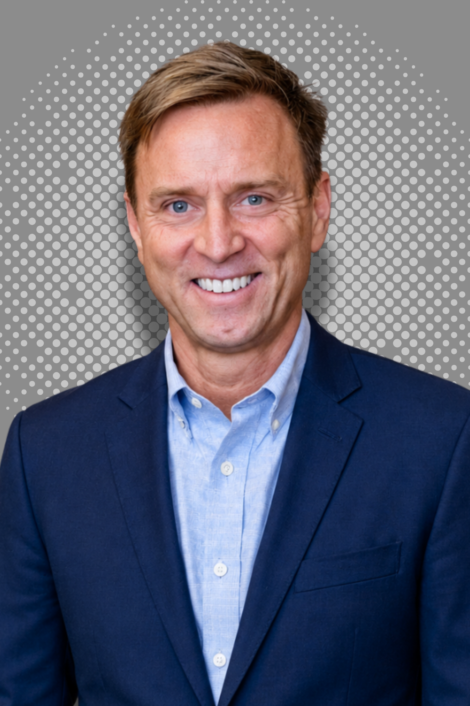Smiling man in a suit with a polka dot background.