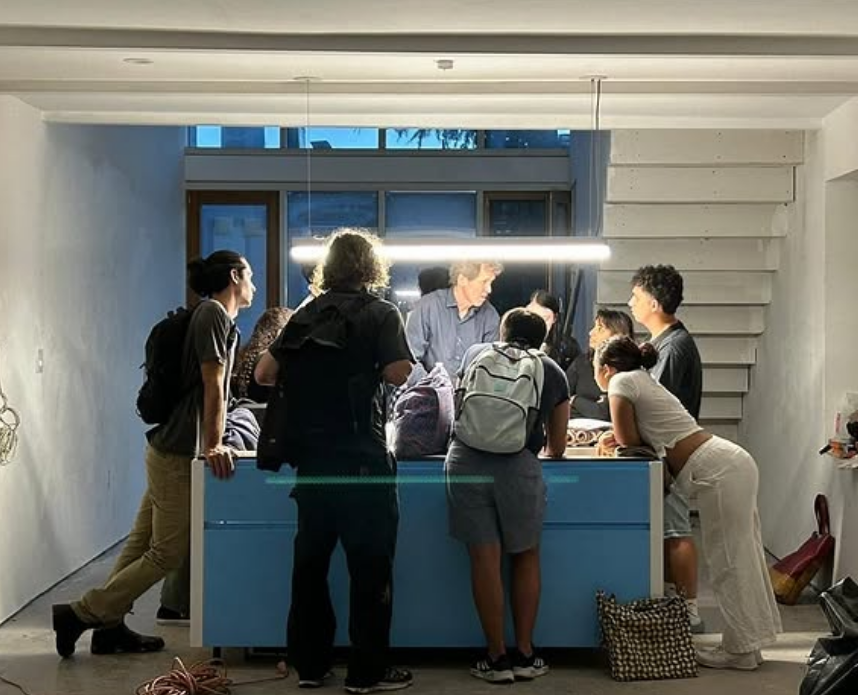 Group of people gathered around a blue kitchen island indoors at night.