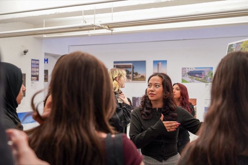 Group of women in an art gallery or exhibition space, engaging in conversation and viewing artwork on the walls.