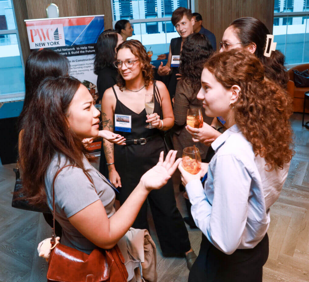 Group of diverse women and men socializing at a professional networking event, holding drinks, with a PWC New York banner in the background.