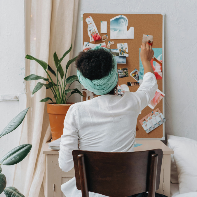 Person placing images on a cork board while building a vision board for self-reflection and clarity