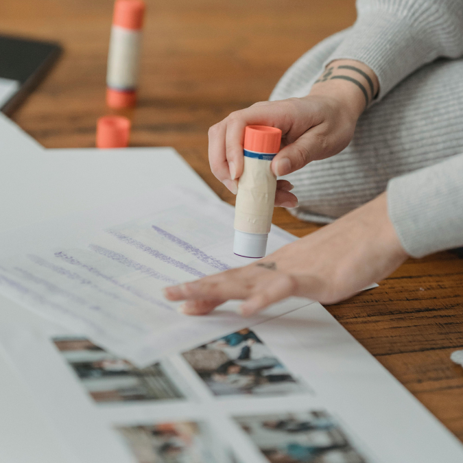 Hands using glue to assemble images for a mental health vision board collage