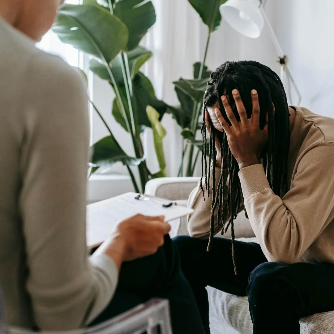 Client sitting in a therapy session with head in hands, reflecting emotional distress and potential therapist red flags.