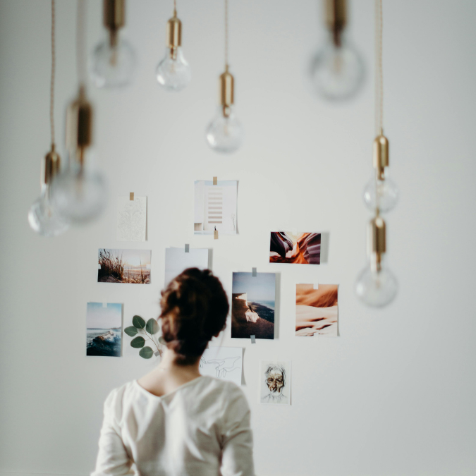Person looking at a simple vision board on a wall, reflecting on mental health goals and personal growth