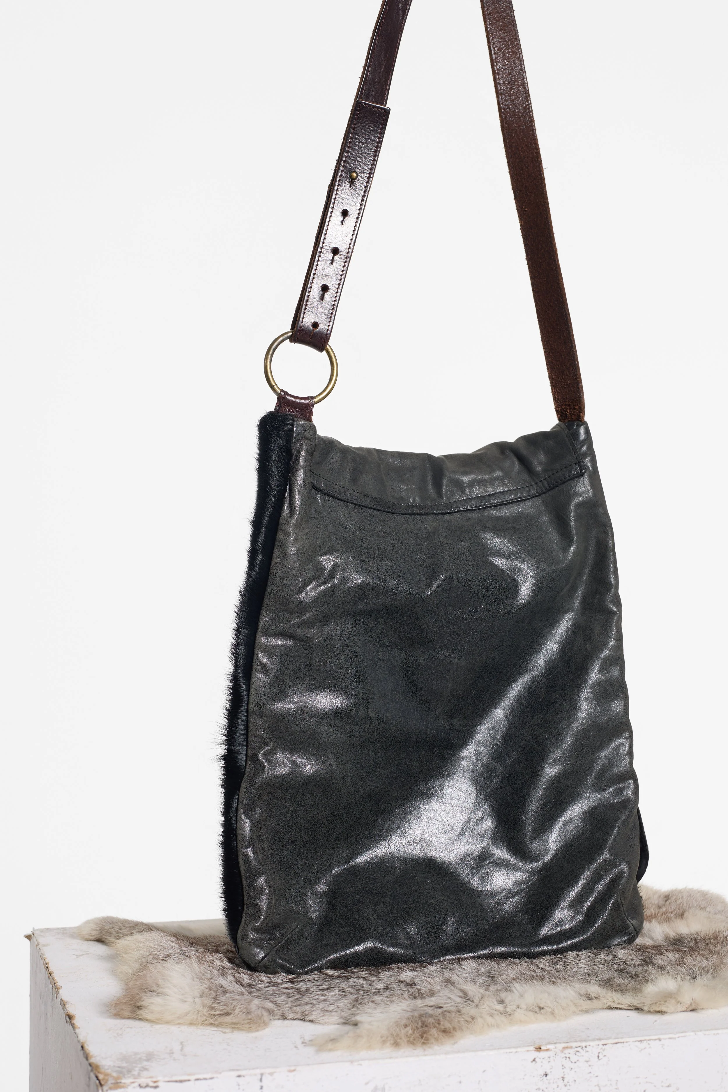 AllSaints vintage cowhide messenger bag photographed on plinth