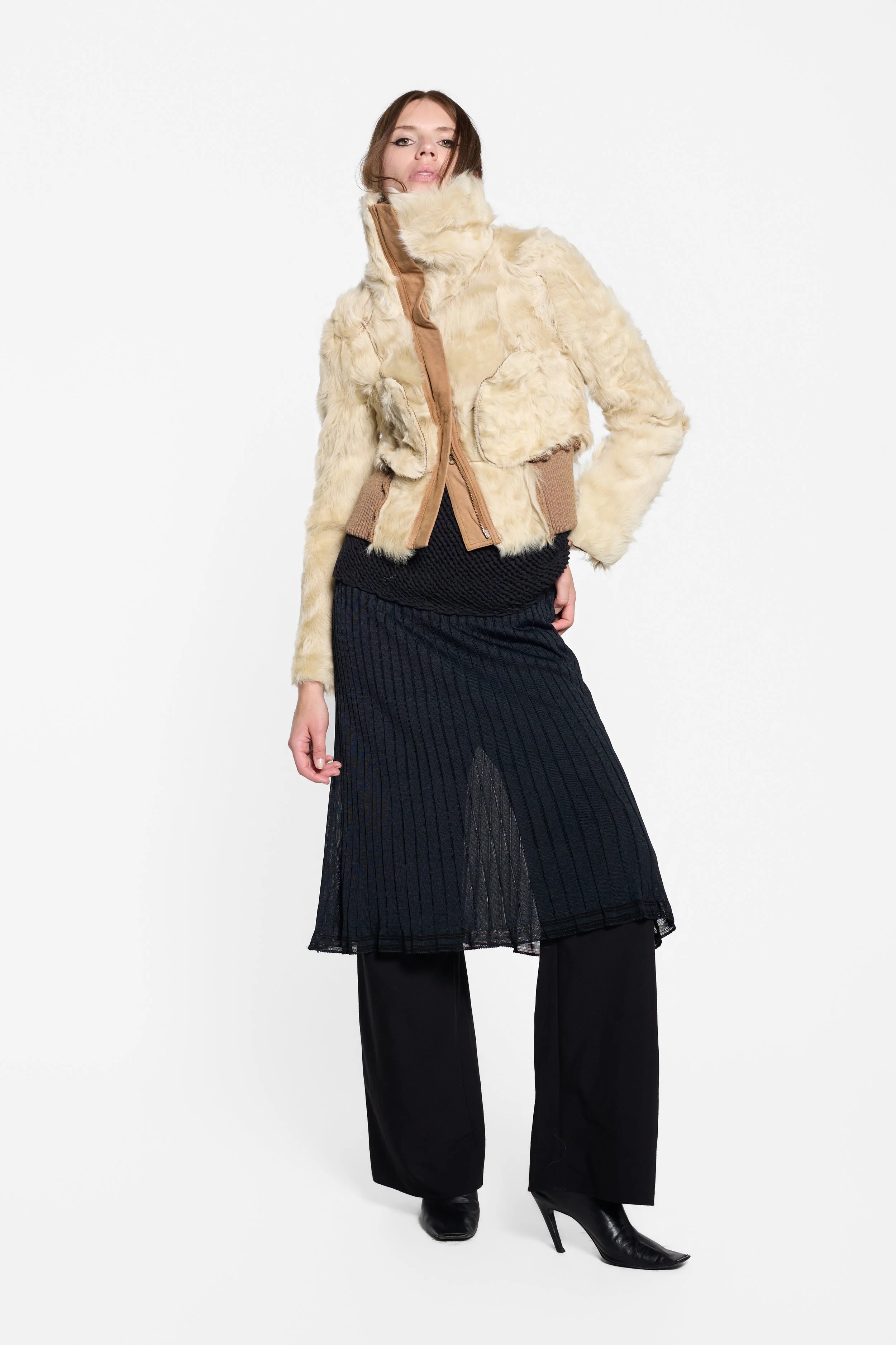 Full-length editorial view of a Chelseagarb lamb fur jacket worn inside out on top of a Hiroko Koshino black knit midi dress