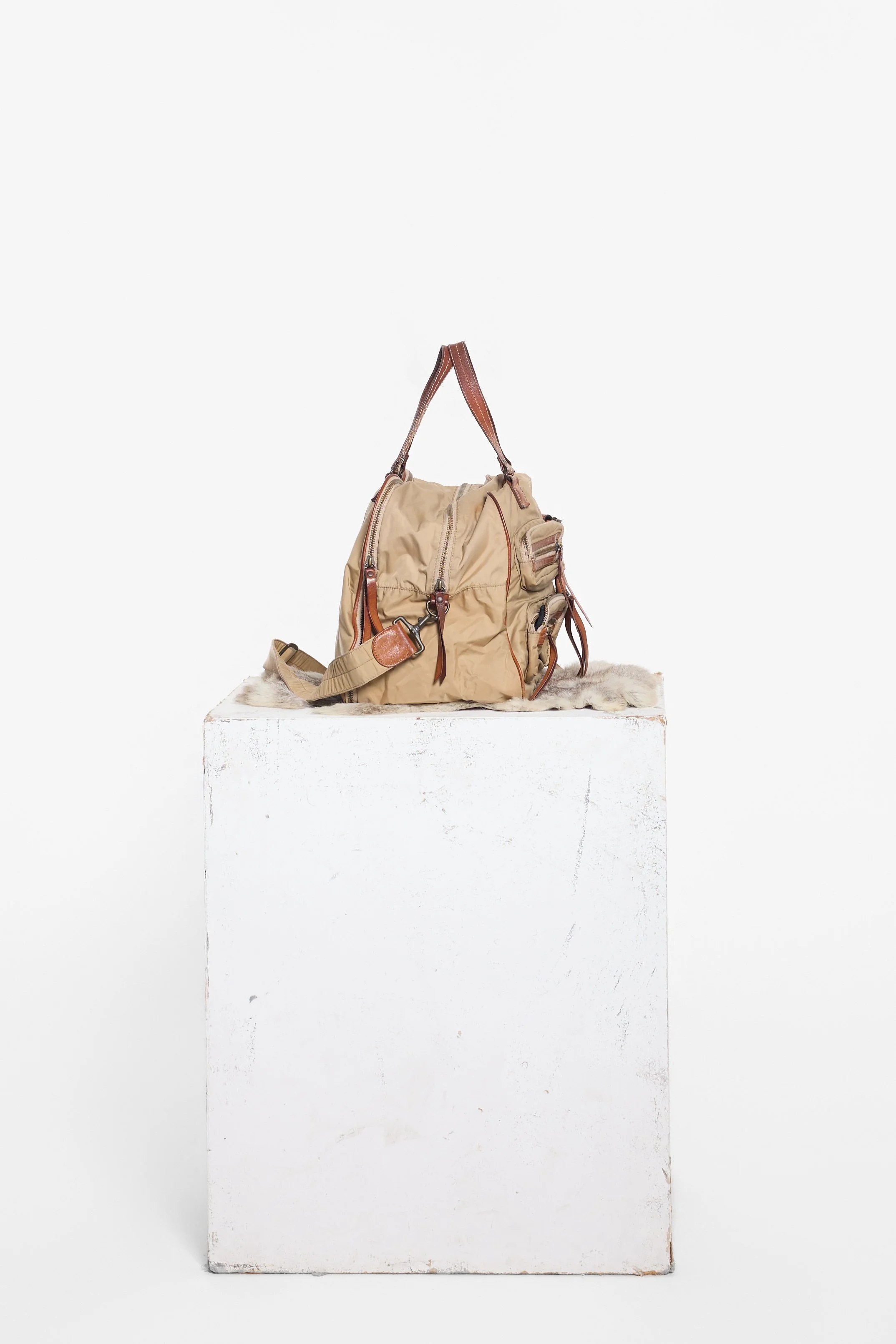 Zoomned out side view of Y'SACCS khaki bag showing wide gusset and shoulder strap hardware