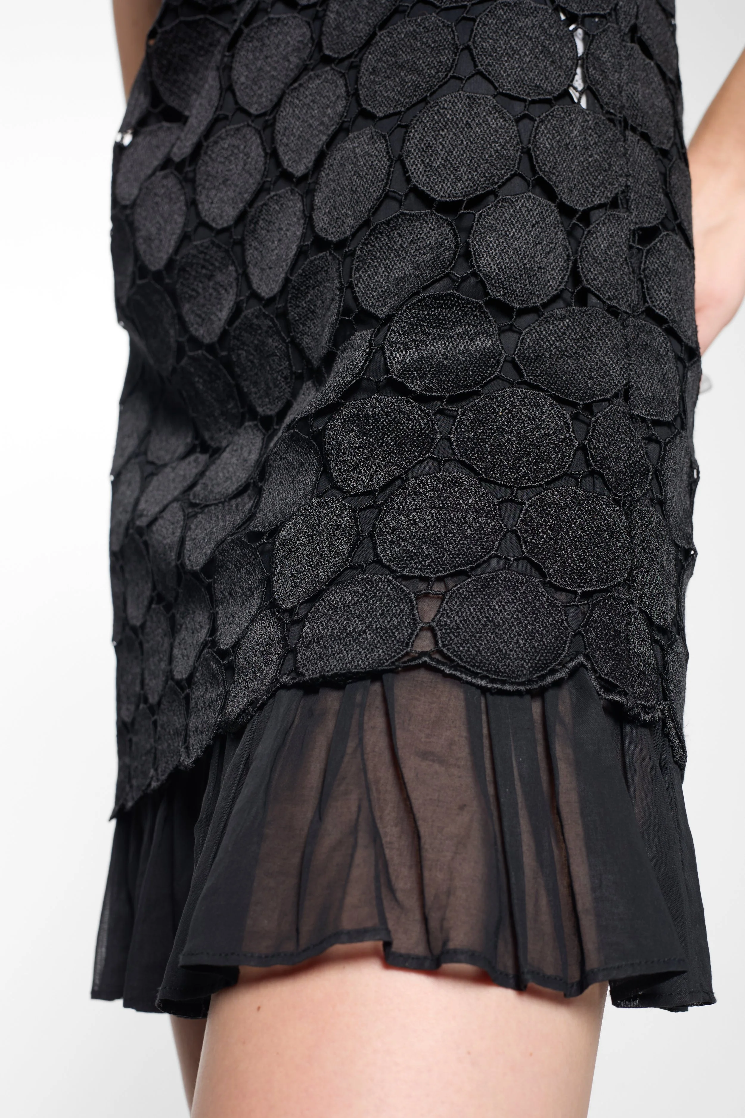 Close-up of scalloped neckline and disc appliqué on LUXXM dress