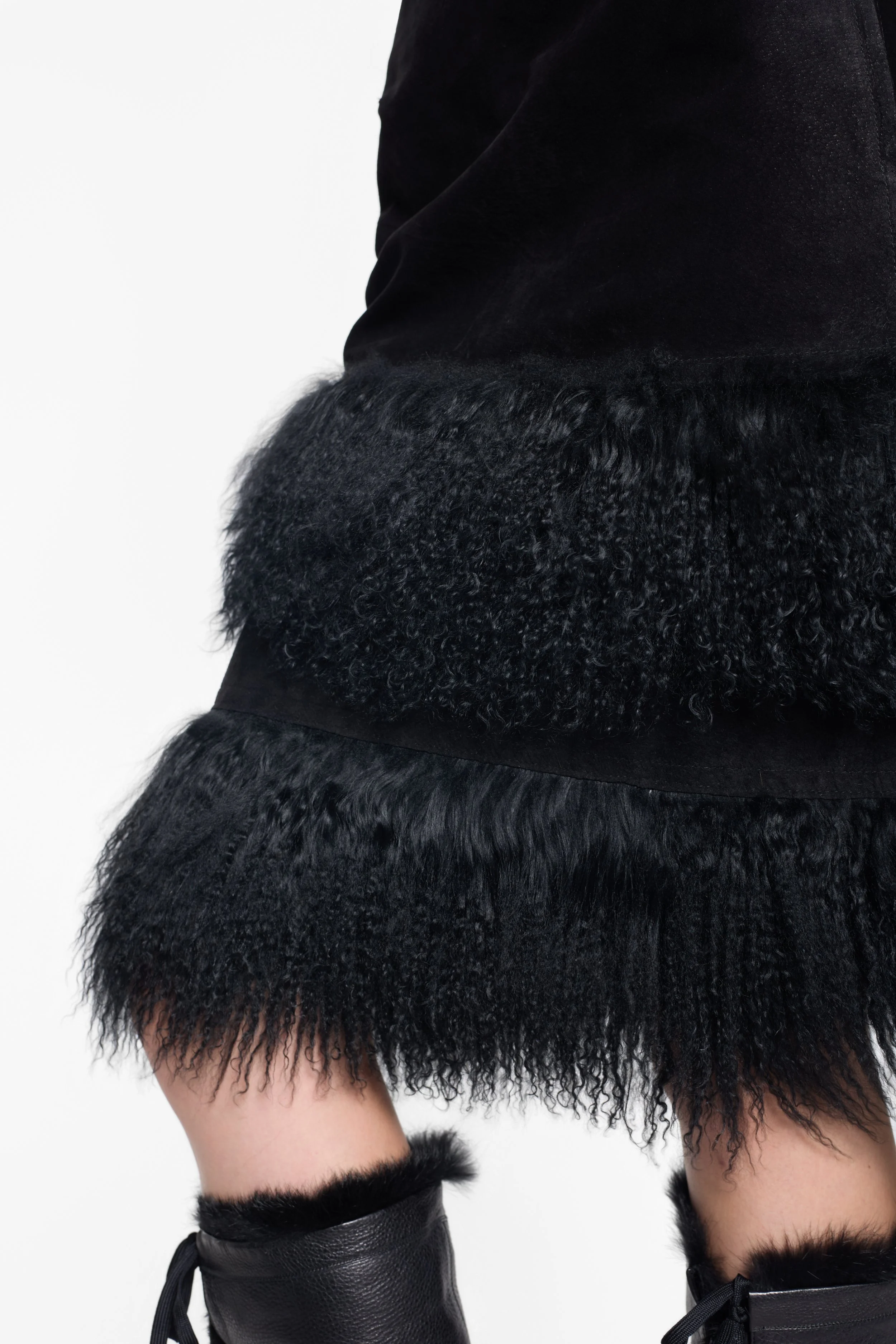 Detail of black leather body and shaggy fur trim on midi skirt