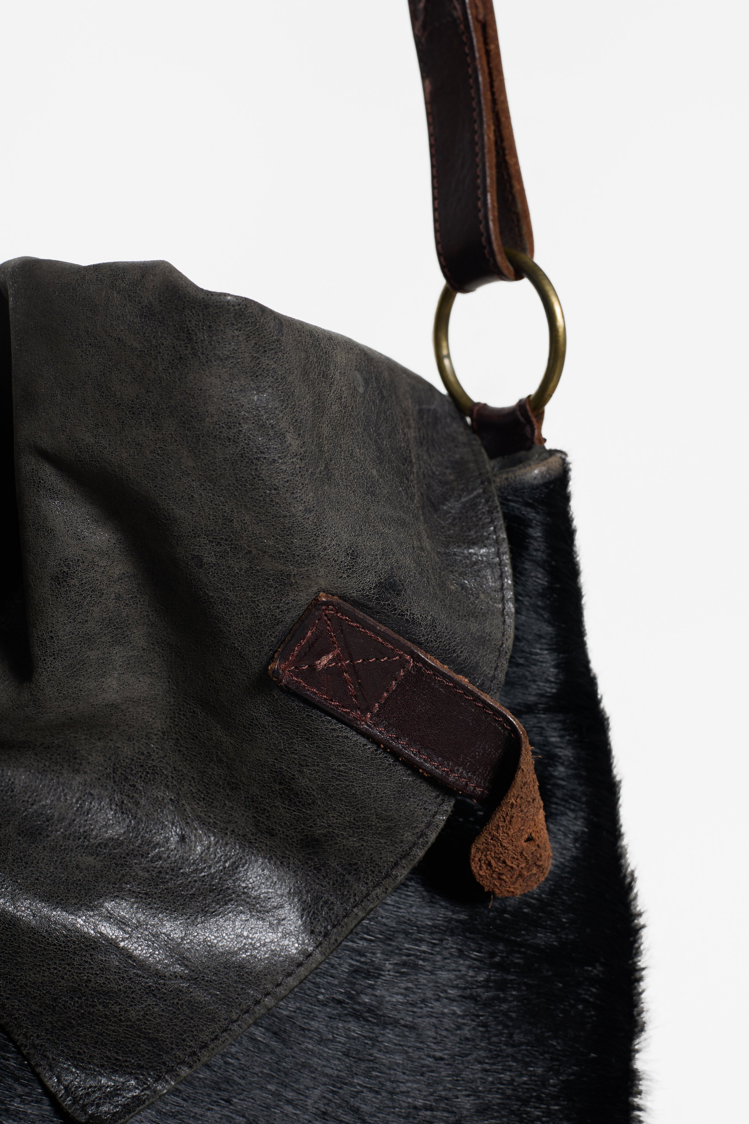 Close-up of AllSaints black cowhide messenger bag with aged charcoal leather flap