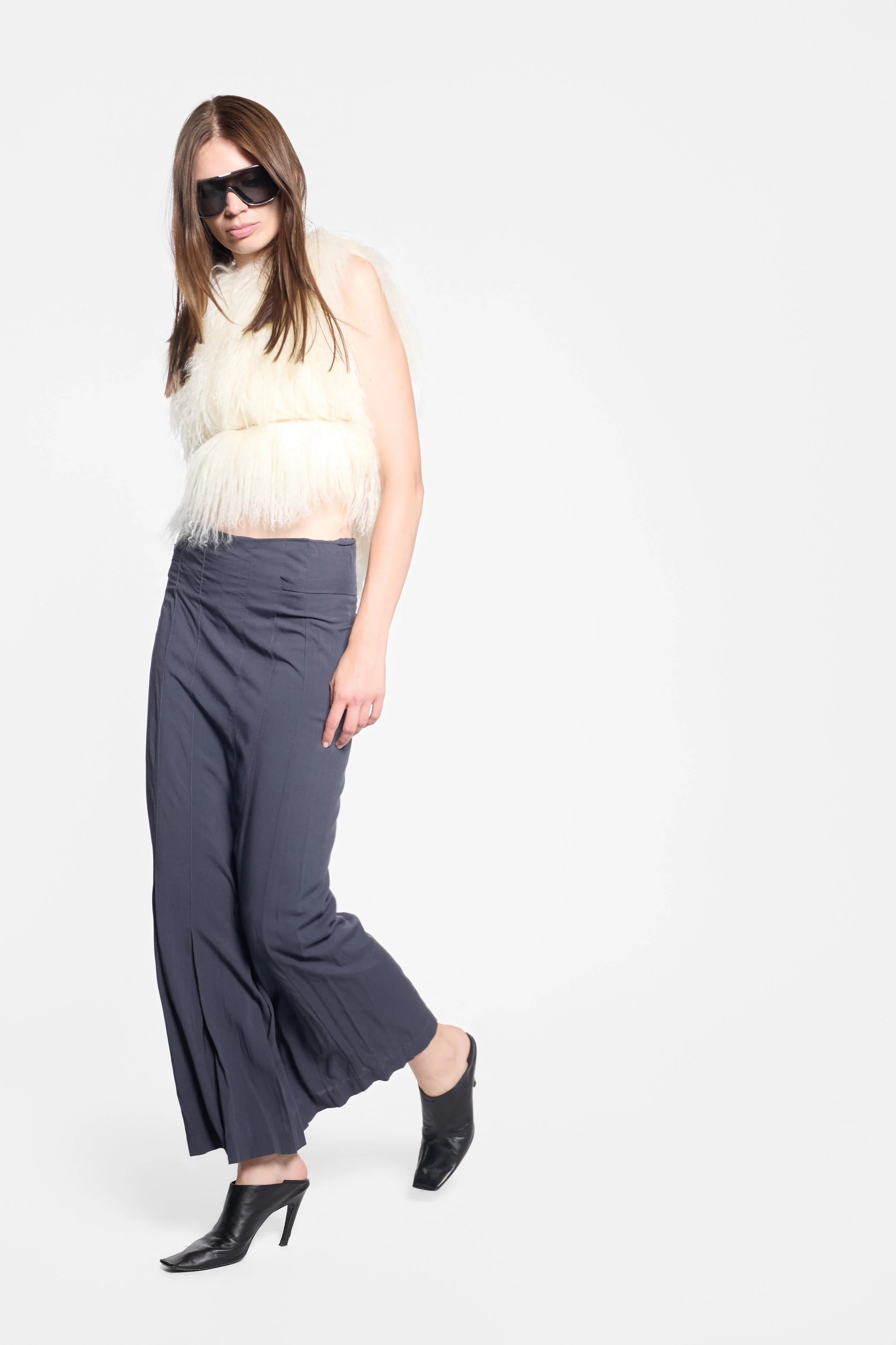 Full-length editorial view of Comme des Garçons navy rayon skirt with white tibet lamb fur gilet and Balenciaga heels