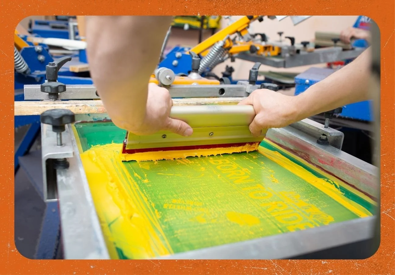 Serigraphy silk screen print process at clothing factory with frame, squeegee and flooding plastisol color paints