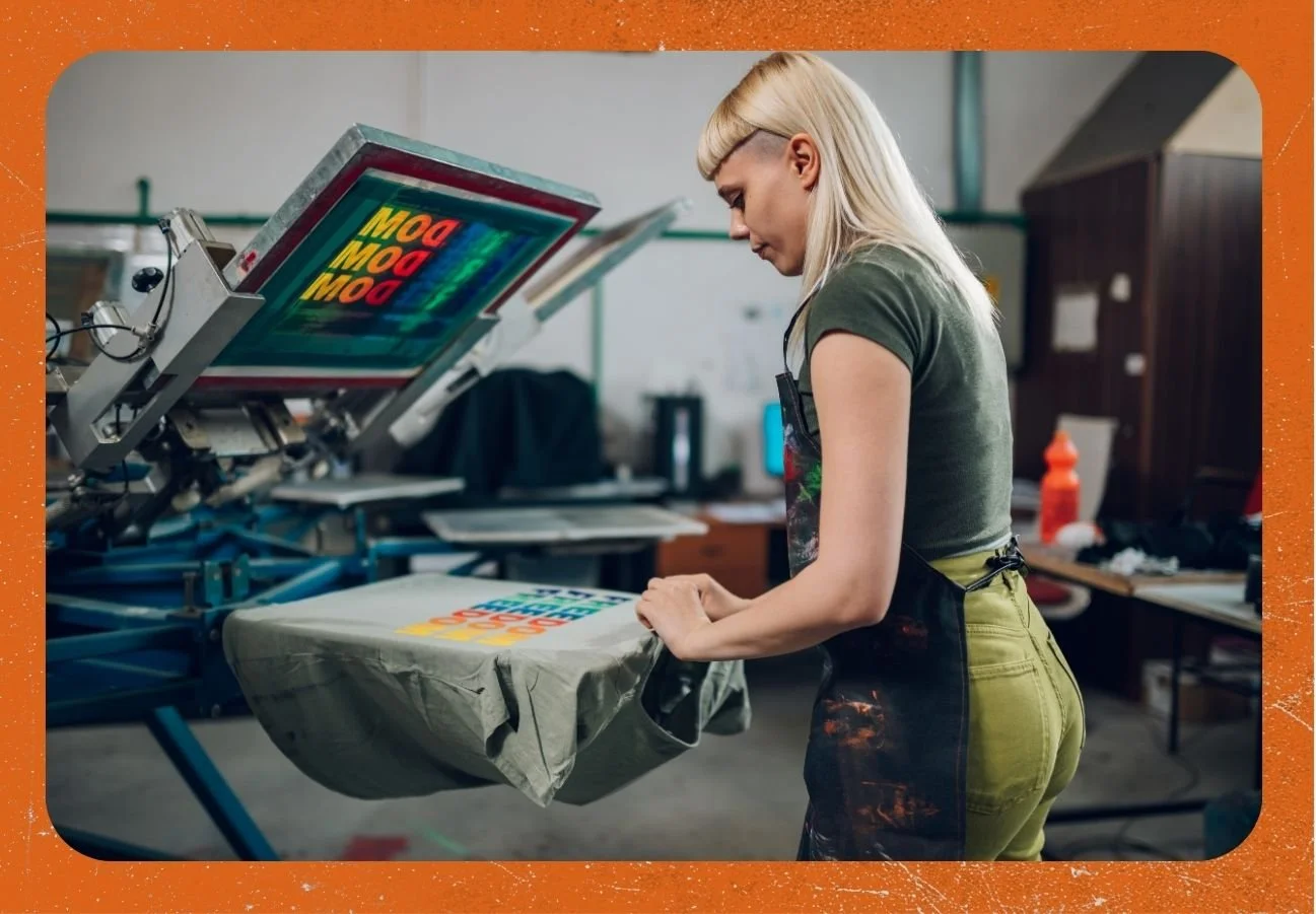 Worker taking screen printed t-shirt off of press at facility