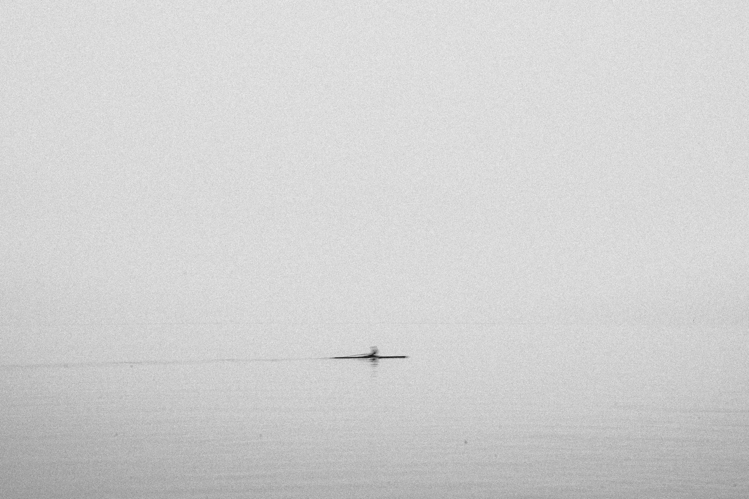 A black and white photo of a boat on a calm body of water.