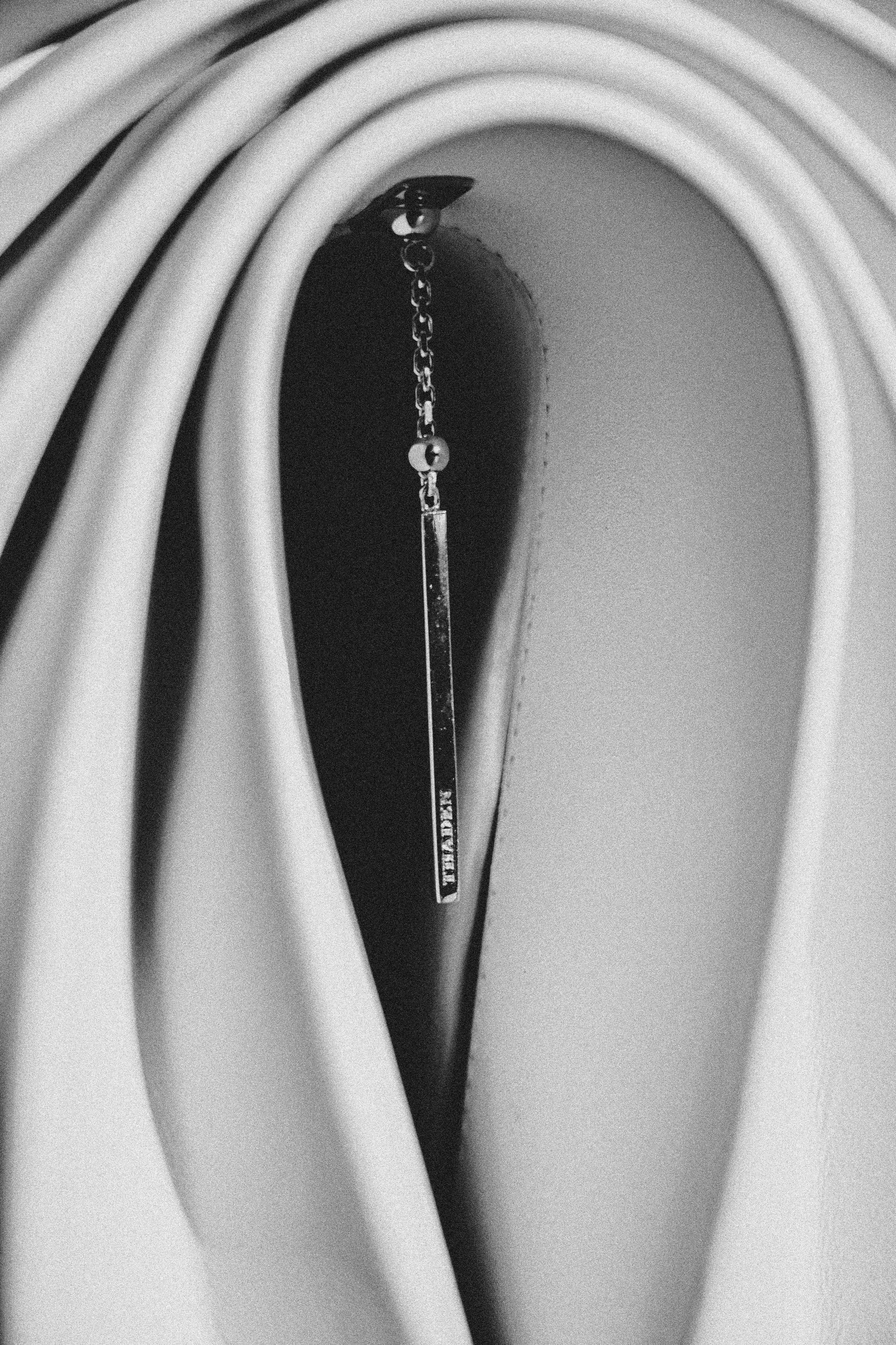 Close-up view of an analog radio tuning dial with a tuning string hanging down, in black and white.